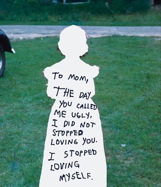 a vintage photograph of a grassy field with a white cutout silhouette of a young girl in the center. the silhouette obscures the girl's face and body. handwritten on the silhouette is a message addressed to "mom," expressing the lasting impact of being called "ugly." it conveys the message that while the child's love for their mother remained, their selflove diminished as a result of the hurtful words.