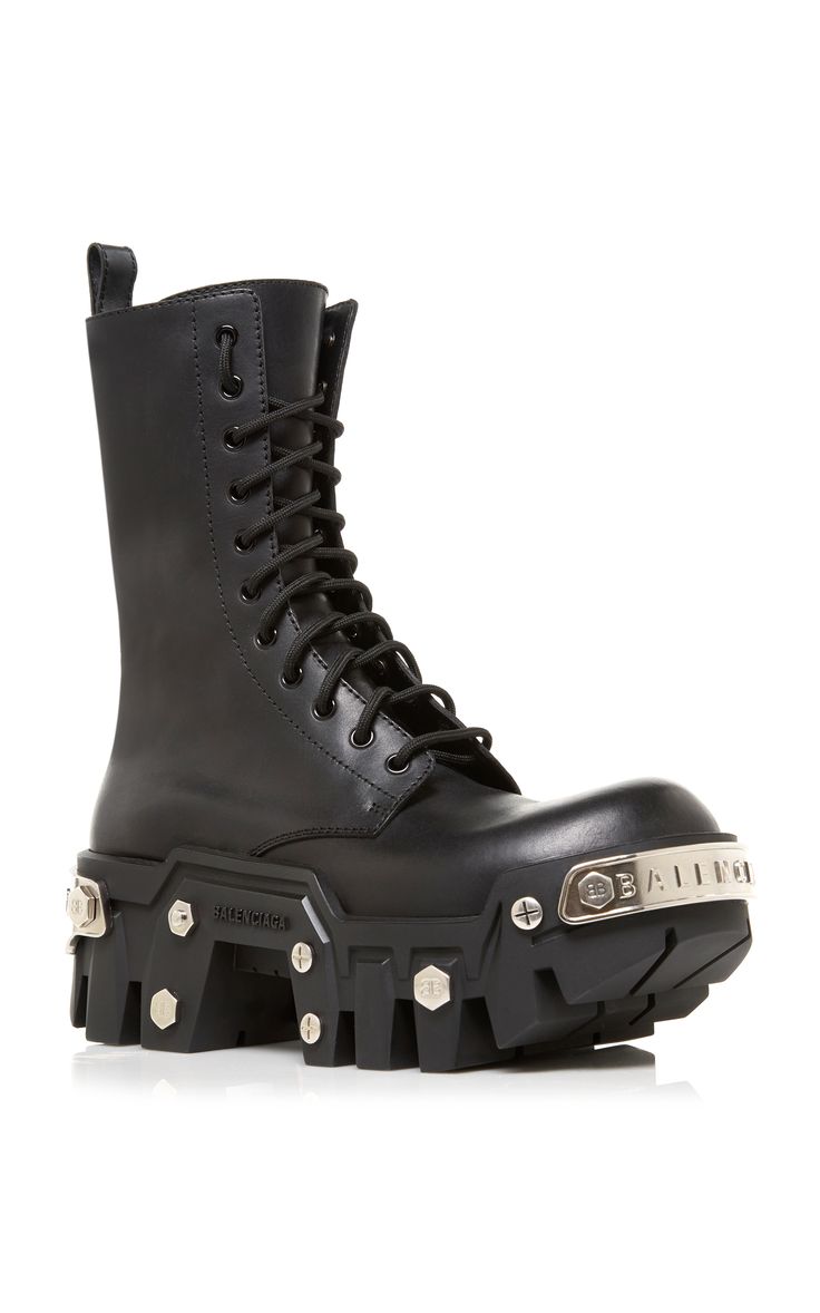 a closeup shot of a pair of balmain black leather combat boots. the boots feature a chunky platform sole, laceup closure, and silver metal hardware details including studs and plates.  the boots are angled slightly to the left, and the background is a plain white studio backdrop.