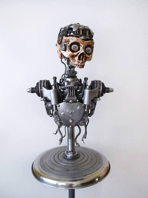 a robot sculpture made of metal and gears, with a human skull head, standing on a metal base.