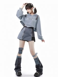 a young woman in a stylish outfit poses in a studio. she is wearing a blue and gray hoodie with a black and gray skirt. she is also wearing blue leg warmers with a black and white stripe design. the woman has her hair down and is looking to the left. she is wearing a casual, trendy look.