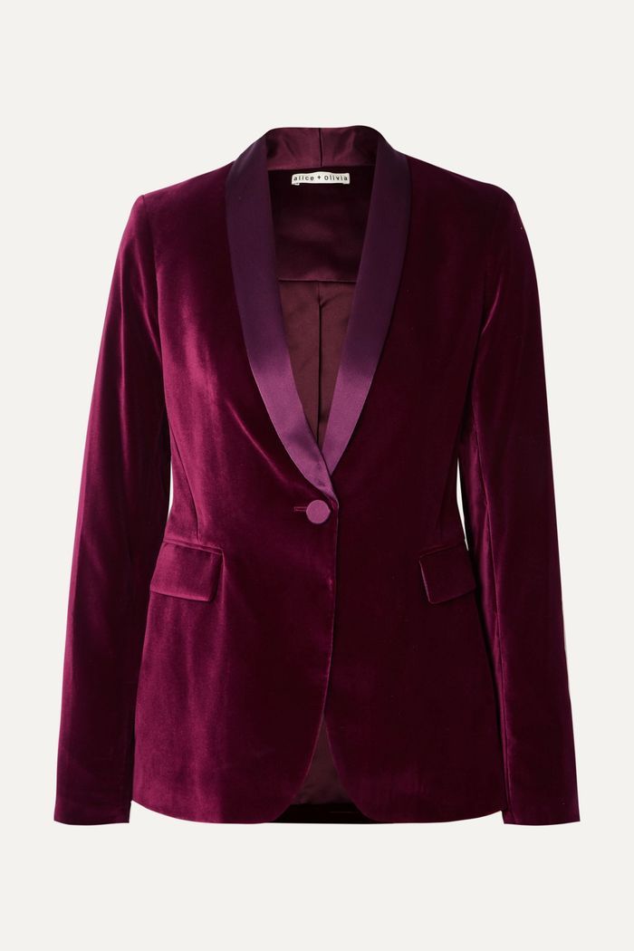 a women's burgundy velvet blazer with a satin collar and button closure. the blazer is longsleeved and has a slim fit. it is a formal and elegant piece of clothing that would be perfect for a special occasion.