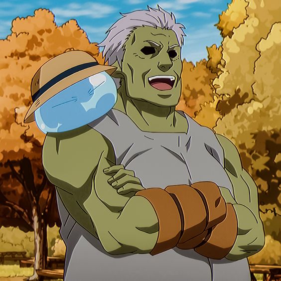 a large greenskinned male character with a friendly smile is shown in the image. he has white hair and a hat on his head.  the character is standing with his arms crossed. he is wearing a grey sleeveless shirt with brown wrist bands. a cartoon bloblike character with a blue body and hat on top of his head is resting on his shoulder. the background shows trees with autumn leaves and a light blue sky.