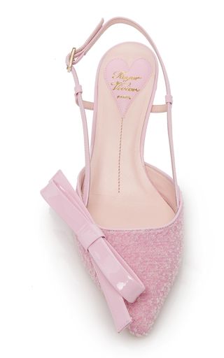 close up of a pair of pink roger vivier women's high heel shoes with a large bow at the toe. the shoes are made of a soft, fuzzy material and have a delicate strap around the ankle. the brand name is embossed on the heel. the shoes are elegant and stylish, perfect for a special occasion.