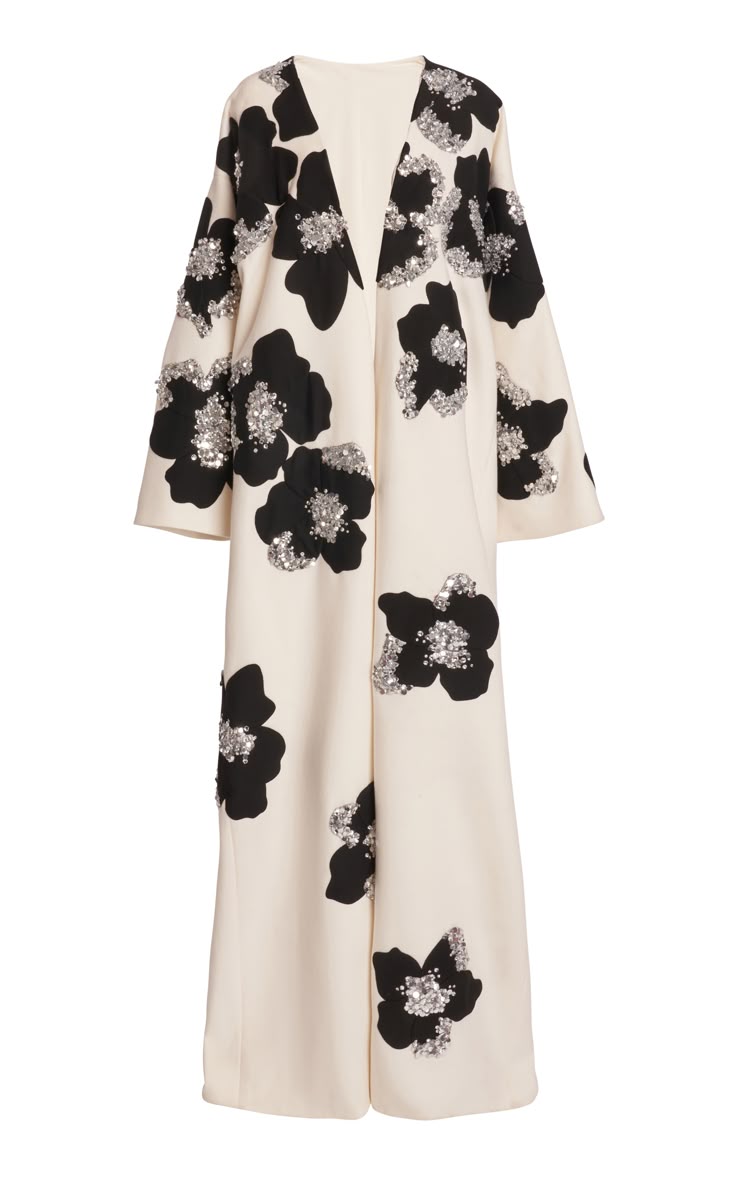 a formal, anklelength dress with an offwhite background and large, black floral patterns. each flower is adorned with shiny sequins. the dress features a vneckline and wide, loose sleeves.