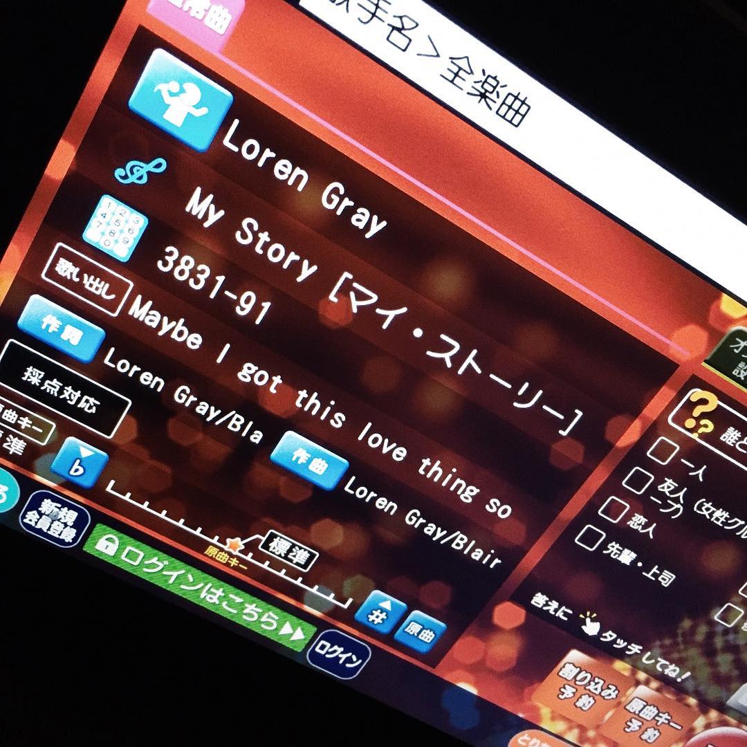 this image shows a karaoke machine touchscreen displaying the song selection screen. the song "my story" by loren gray is highlighted, with the song title in english and japanese. the screen also shows the song number (383191), a snippet of the lyrics ("maybe i got this love thing so"), the names of the songwriters (loren gray/blair), and various options for adjusting the song key and original pitch. the screen also includes options in japanese for different karaoke settings and login functionality.