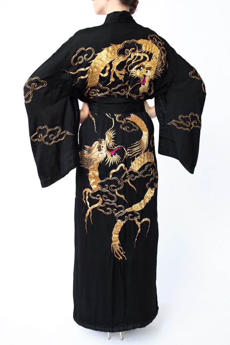 a back view of a person wearing a long black kimono with gold dragon embroidery. the kimono has wide sleeves and a belt, and the dragons are detailed with red accents.