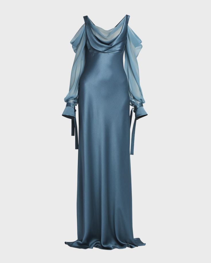 the image shows a long, flowing blue silk gown. the dress features a cowl neck, cold shoulder design, and sheer sleeves with ties at the cuffs. the fabric appears to be a luxurious satin.  the overall style is elegant and formal, suitable for an evening event or special occasion. the dress is shown on a white background, and is presented in a fulllength view.