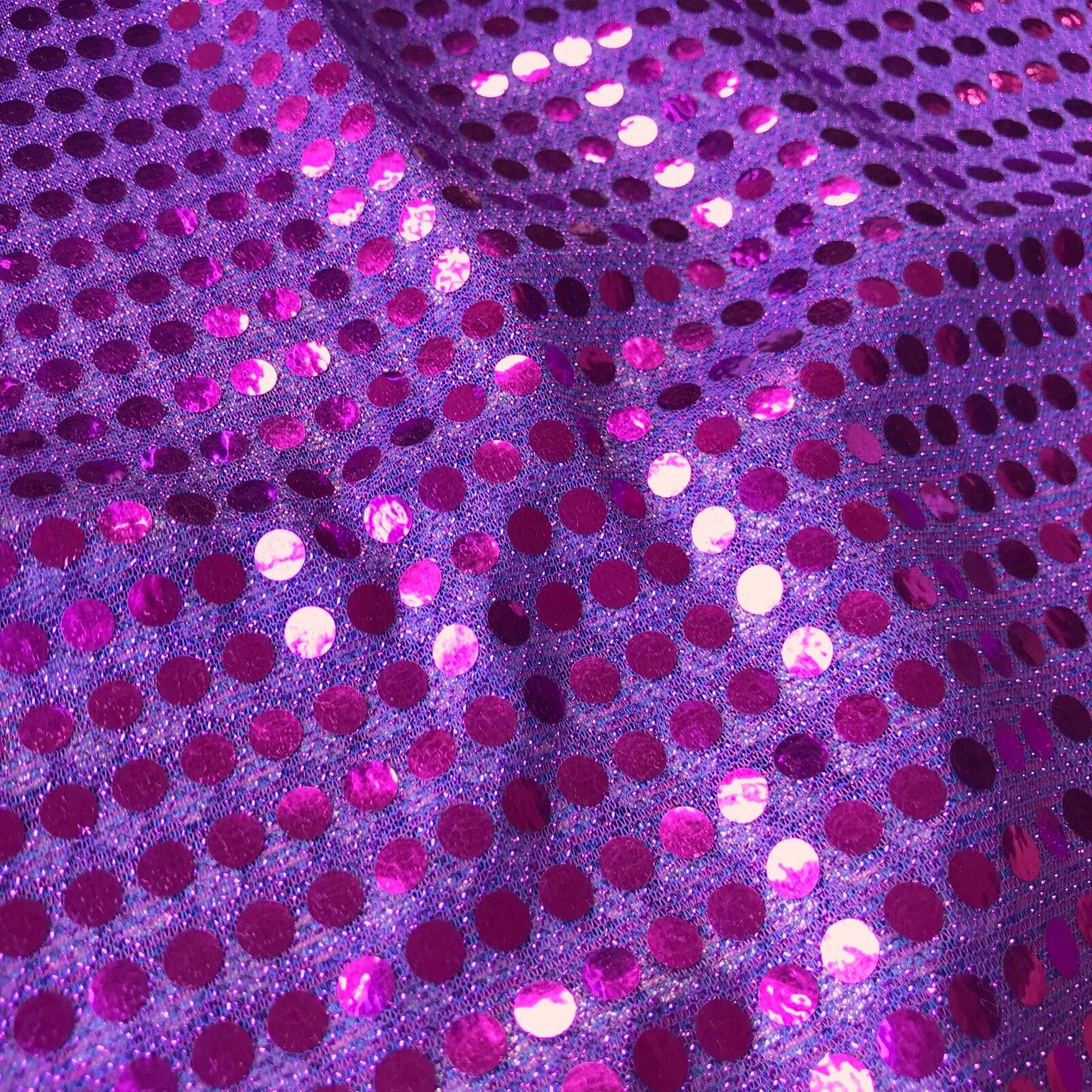 a closeup image of shiny purple sequined fabric. the sequins are small and closely packed together, creating a textured and sparkly surface. the fabric is wrinkled slightly, adding to its visual interest. the overall effect is one of glamour and celebration.
