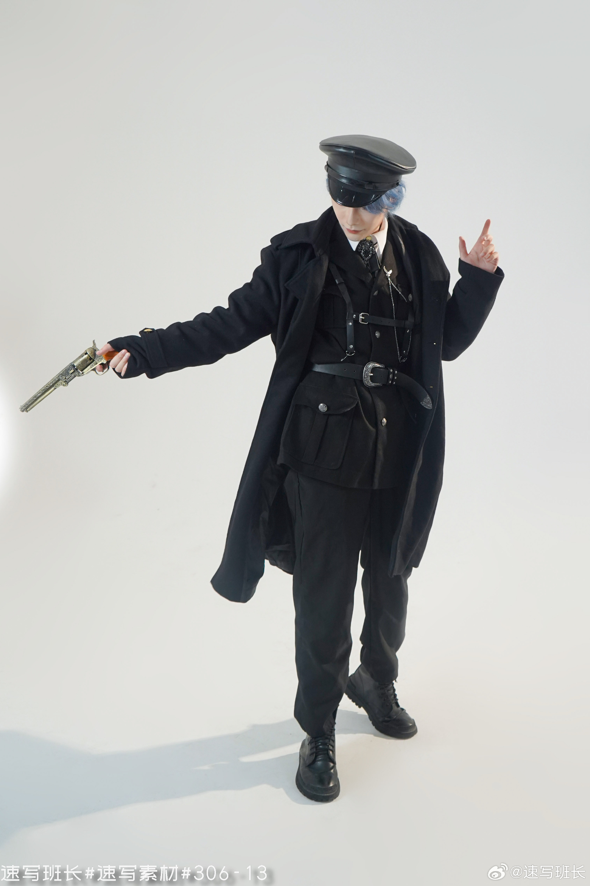 a man in an elaborate militaryinspired outfit stands against a white background. he is holding a gun in his right hand and his left hand is raised with his index finger pointed. he is wearing a black trench coat, black pants, a black vest with various buckles and straps, a white shirt with a black tie, a black peaked cap, and black boots. he has short, blue hair and is wearing black eyeliner. the lighting is soft and diffused, creating a dramatic effect.