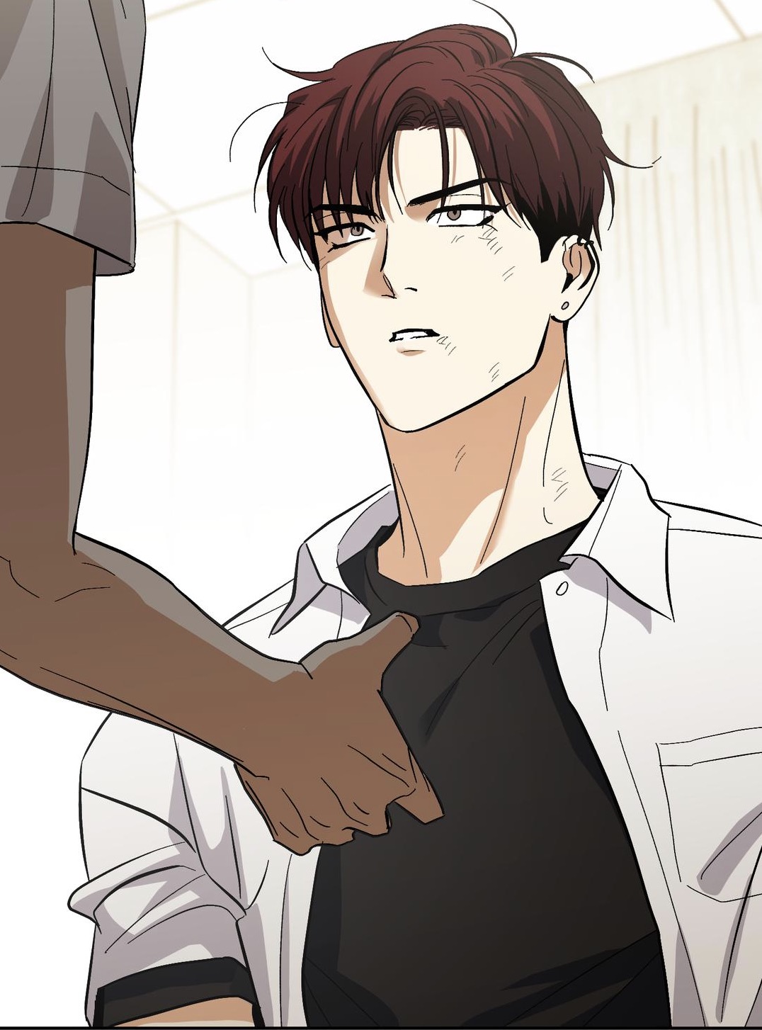 the image is a closeup illustration or scan from a manga or comic book. it depicts a young adult male character with reddishbrown hair and a slightly distressed expression. he's wearing a dark shirt under a lightcolored, open buttondown shirt. a darkerskinned hand, presumably belonging to another character, is visible reaching toward the main character's chest. the background is blurred and light, focusing the viewer's attention on the man's face and the interaction between the two characters.  the style is consistent with popular korean webtoons or manhwa.
