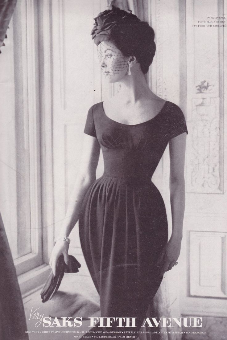 a black and white vintage advertisement for saks fifth avenue features a woman wearing a black dress with short sleeves and a fitted waist. she is wearing a hat with a veil, earrings, and jewelry. she is holding gloves in her hand. the ad is for saks fifth avenue and lists various locations.