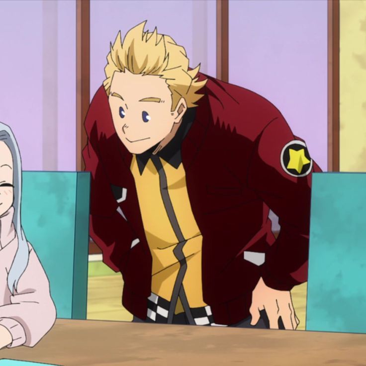 the image shows an anime character, a young blondehaired boy, wearing a red and yellow hero costume with a black star on his sleeve. he is sitting at a table in a classroom, smiling and looking at someone offscreen. the character appears cheerful and friendly.