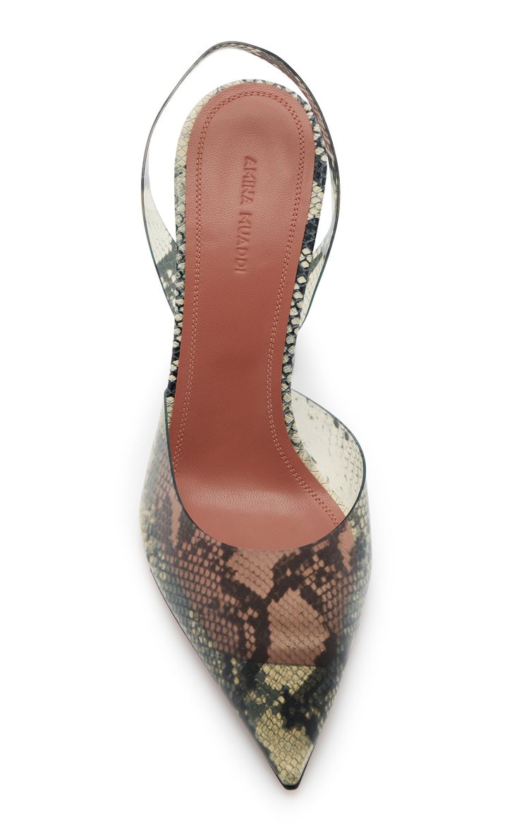 a topdown studio shot of a pair of amina muaddi slingback heels. the heels are transparent with a snake print pattern. the shoes have pointed toes and a high heel. the brand name is visible on the insole. the background is white.