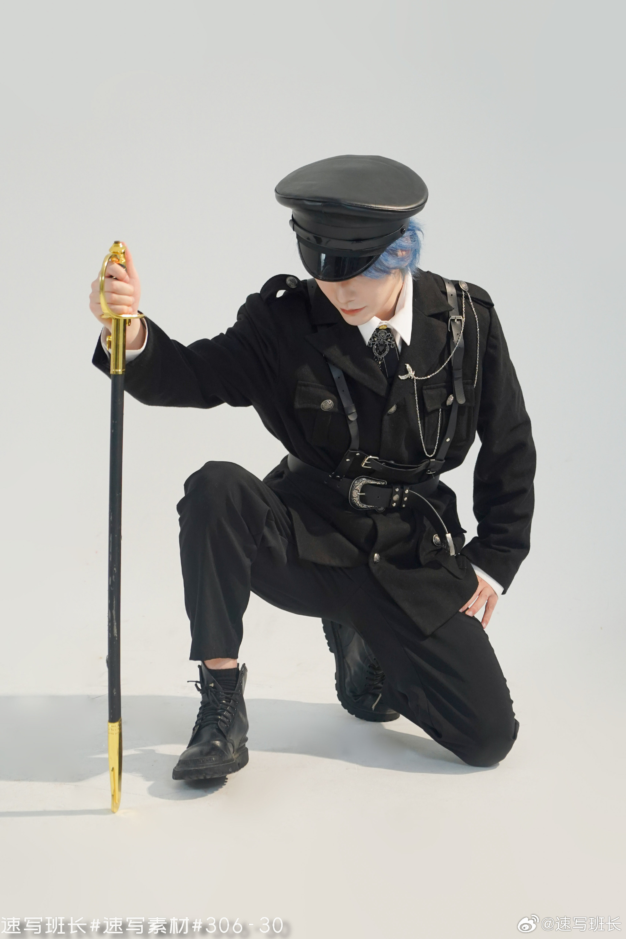 a young man with blue hair, dressed in a black militarystyle uniform with gold accents, is kneeling and holding a gold sword. he is posing against a white backdrop in a studio setting.