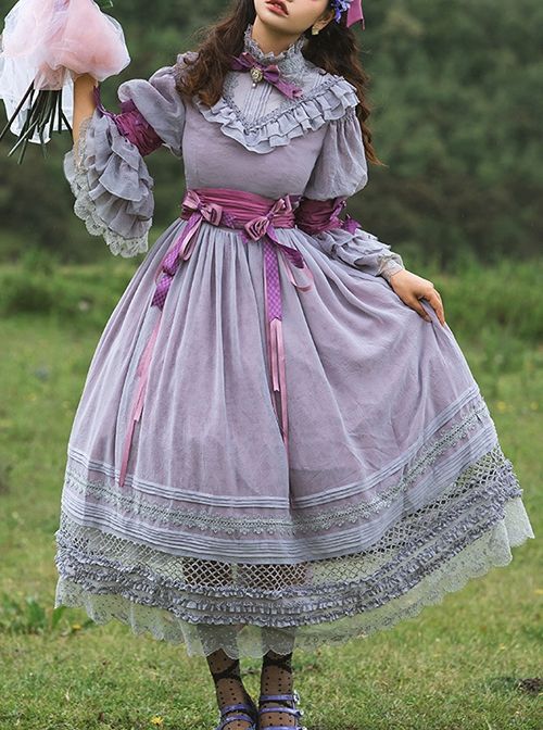a woman in a flowing purple dress stands in a field, holding a bouquet of flowers. the dress is adorned with lace and ruffles, and the woman is wearing a matching headband. the photo is taken from an eyelevel perspective, and the lighting is natural and soft. the overall feel of the image is romantic, ethereal, and dreamy.