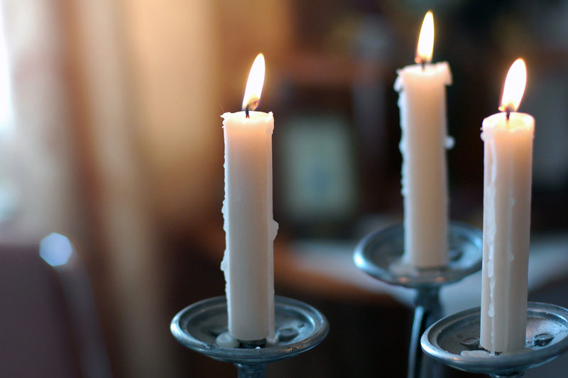 three white candles are burning in silver holders. the candles are tall and thin, with a slight taper. the flames are flickering and casting a warm glow on the surrounding area. the background is out of focus and blurred, which adds to the romantic and intimate ambiance of the scene. the image is a simple and elegant depiction of candlelight, which can be used to create a cozy and relaxing atmosphere in any home.