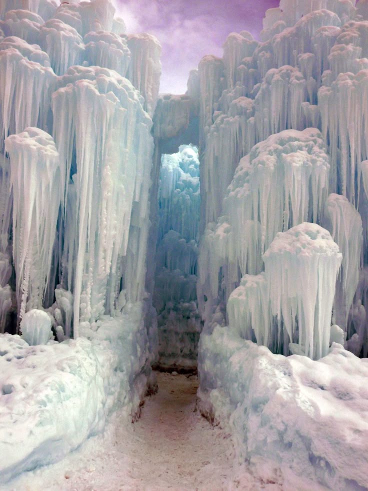 the image depicts a snowcovered tunnel carved through an impressive ice castle structure. massive icicles hang from the ceiling, forming a frozen landscape. the scene exudes a wintery, icy atmosphere.