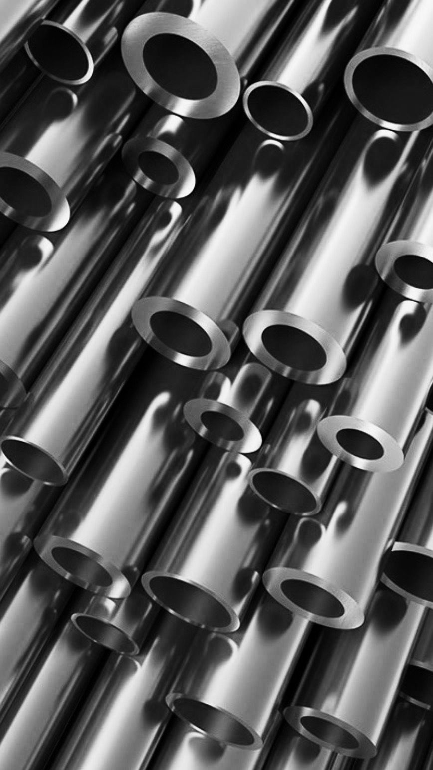 the image showcases a collection of stainless steel pipes, meticulously arranged. the metallic surfaces gleam under the focused studio lighting, highlighting the cylindrical forms and creating an interplay of light and shadow.