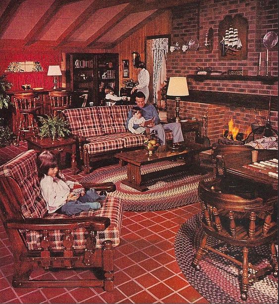 the image shows a 1970s family in their living room. the room is decorated in warm colors with plaid furniture, a brick fireplace, and wood paneling. the father is reading to his son on the couch, while the mother stands in the background and the daughter reads in a rocking chair. the overall feeling of the image is one of warmth, coziness, and family togetherness.