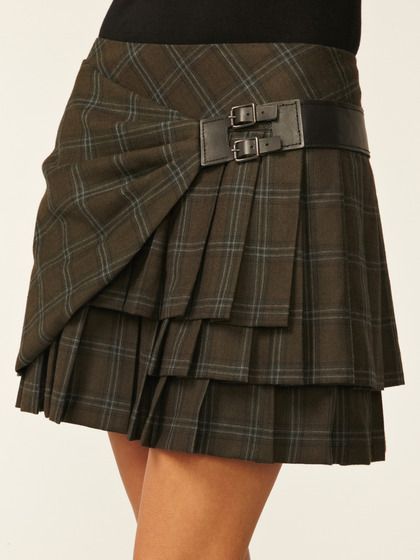 a woman wears a brown, plaid, tiered mini skirt with pleats and a black buckle belt.