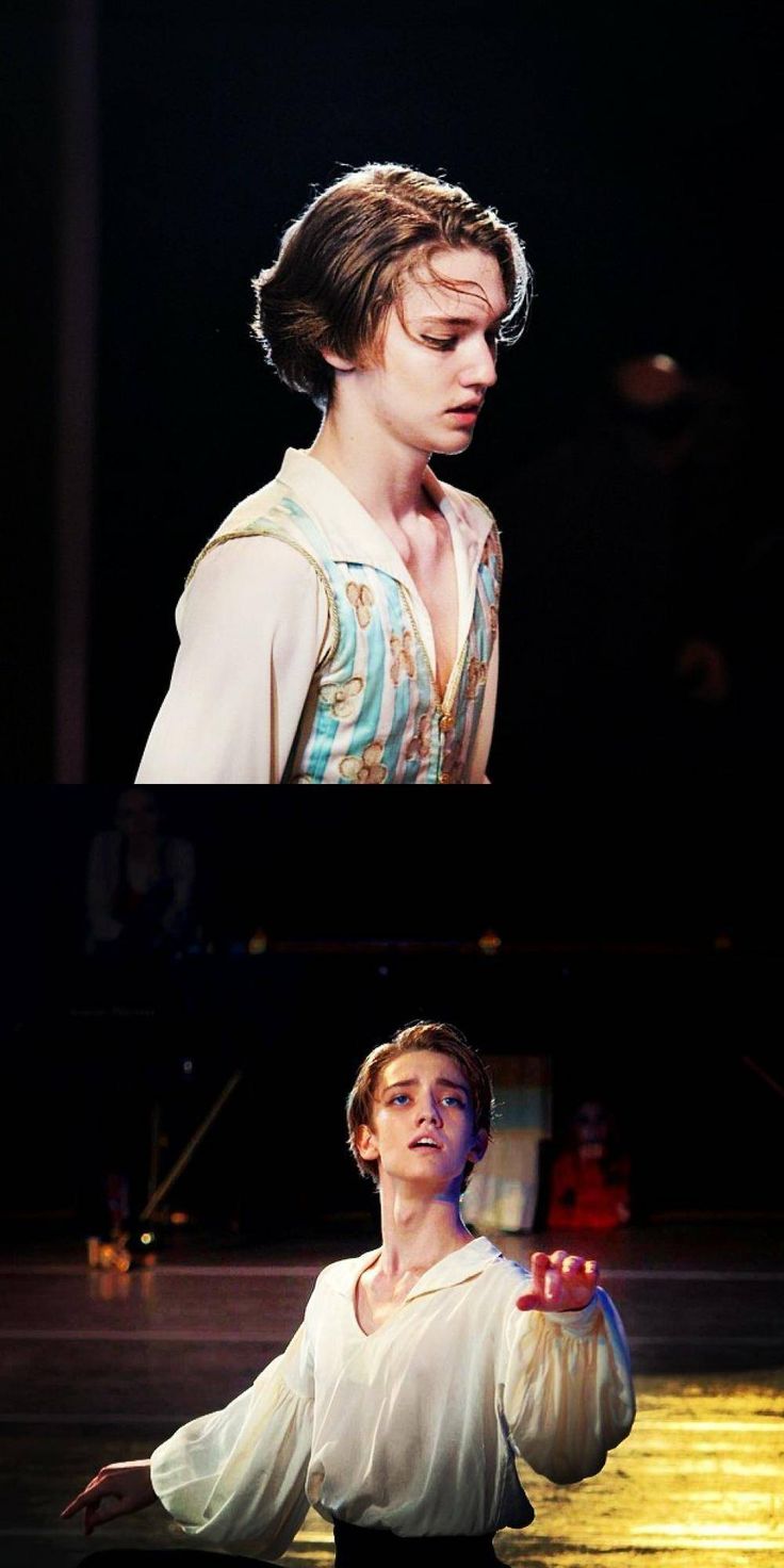 a young man, possibly a ballet dancer, poses on a stage, illuminated by spotlights, dressed in a costume reminiscent of a historical period piece. the image appears to be a captured moment from a theatrical performance.