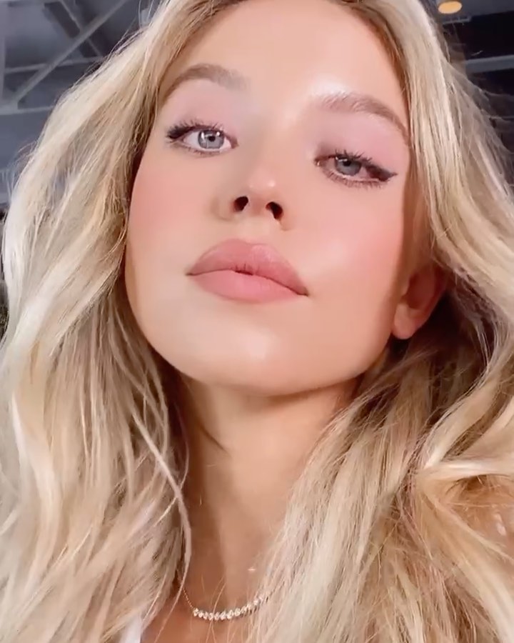 closeup portrait of a beautiful young blonde woman with soft, subtle makeup.  her hair is long and wavy, cascading around her shoulders. she is wearing a delicate necklace and her expression is serene and slightly alluring. the focus is on her flawless skin and light, natural makeup. the overall aesthetic is soft, elegant, and feminine.