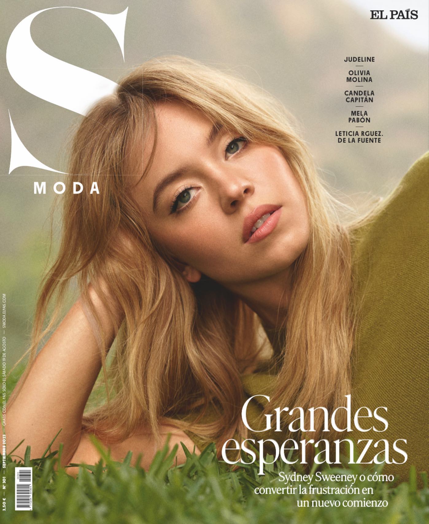 this is a magazine cover featuring sydney sweeney. the cover is for el país's moda section.  the title reads "grandes esperanzas" (great hopes) and features a subheading about sweeney and turning frustration into a new beginning.  the cover also lists other names, possibly contributing writers or other featured individuals. sweeney is pictured lying in the grass, wearing a green sweater, with her blonde hair cascading around her shoulders.  the overall tone is one of beauty, hope, and perhaps a hint of introspection.