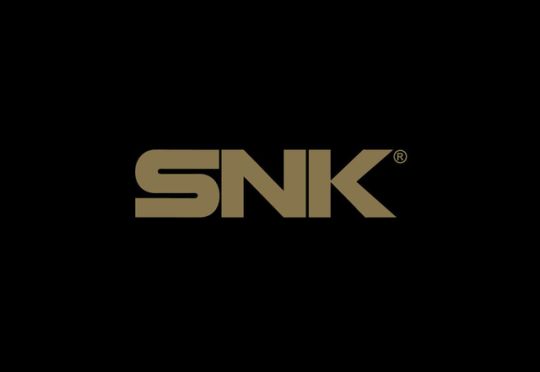 the image is a logo for the video game company snk. the logo features the letters "snk" in a bold, sansserif font. the letters are all capitalized and are set in a horizontal line. the logo is a dark brown color and is set against a black background. there is a small registered trademark symbol to the right of the "k"