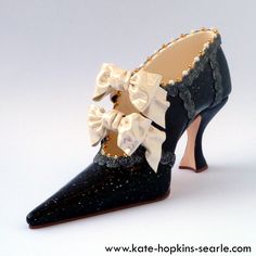 a  black high heeled shoe with a black lace top and ivory bow. it is a delicate and elegant shoe that would be perfect for a special occasion.