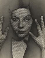 the image is a striking black and white closeup portrait of a woman. her face and hands are prominently featured, while her body is partially obscured.  the most notable characteristic is a textured, meshlike overlay or effect applied to the photograph giving a screenprinted or halftonelike appearance. her expression is serious and slightly enigmatic. the hands are posed expressively, framing the face.  the overall style evokes a sense of mystery and artistry, reminiscent of early to mid20thcentury experimental photography. the dark tones and the textured effect add to the image's dramatic and somewhat surreal quality.