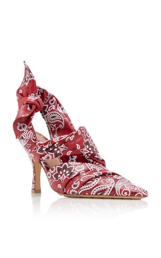 a pair of red leather heeled shoes with a paisley print. the shoes are pointed toe and have a slingback design.