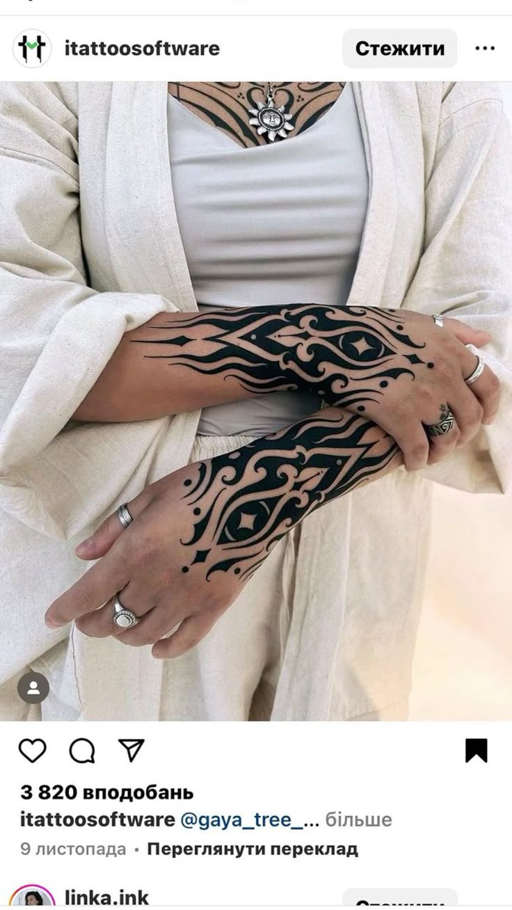 a person is wearing forearm and hand tattoos and rings on their fingers. the person is also wearing a white shirt and a cardigan and a necklace. their arms are crossed. the image is from an instagram post from @itattoosoftware.