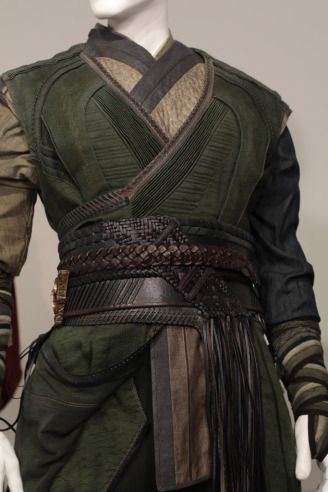 the image showcases a detailed costume, likely from a film or theatrical production. the attire, with its layers of green and brown fabric, a wrapped and braided belt, and various textures, suggests a sorcerer or mystical character, possibly inspired by dr. strange.