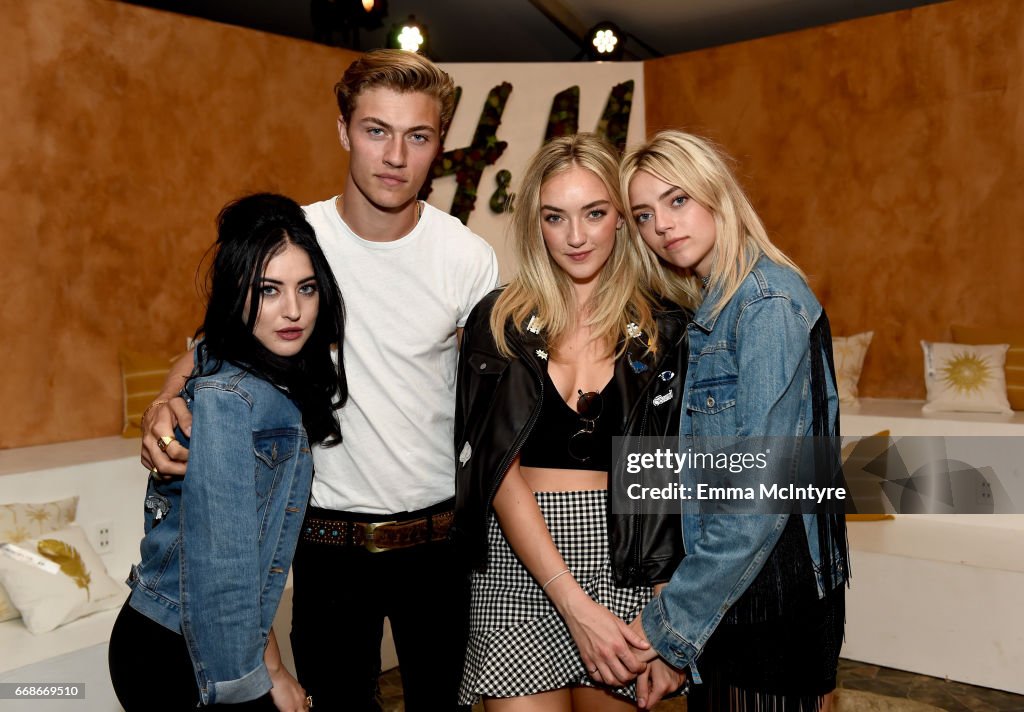 a group of four people are posing for a photo in front of an h&m logo. there are three women and one man. the women are wearing denim and leather jackets, and the man is wearing a white tshirt. the photo is taken at an event, and there is a getty images watermark in the corner.