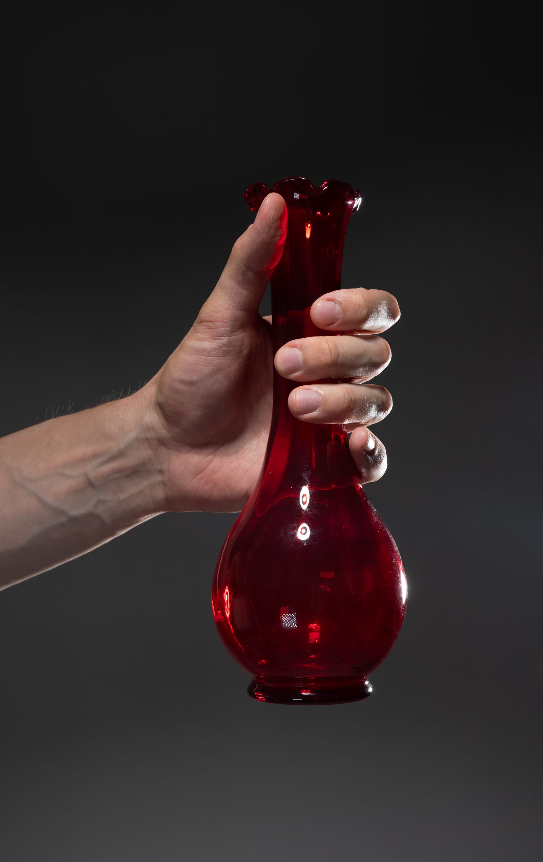a hand holding a red glass vase.