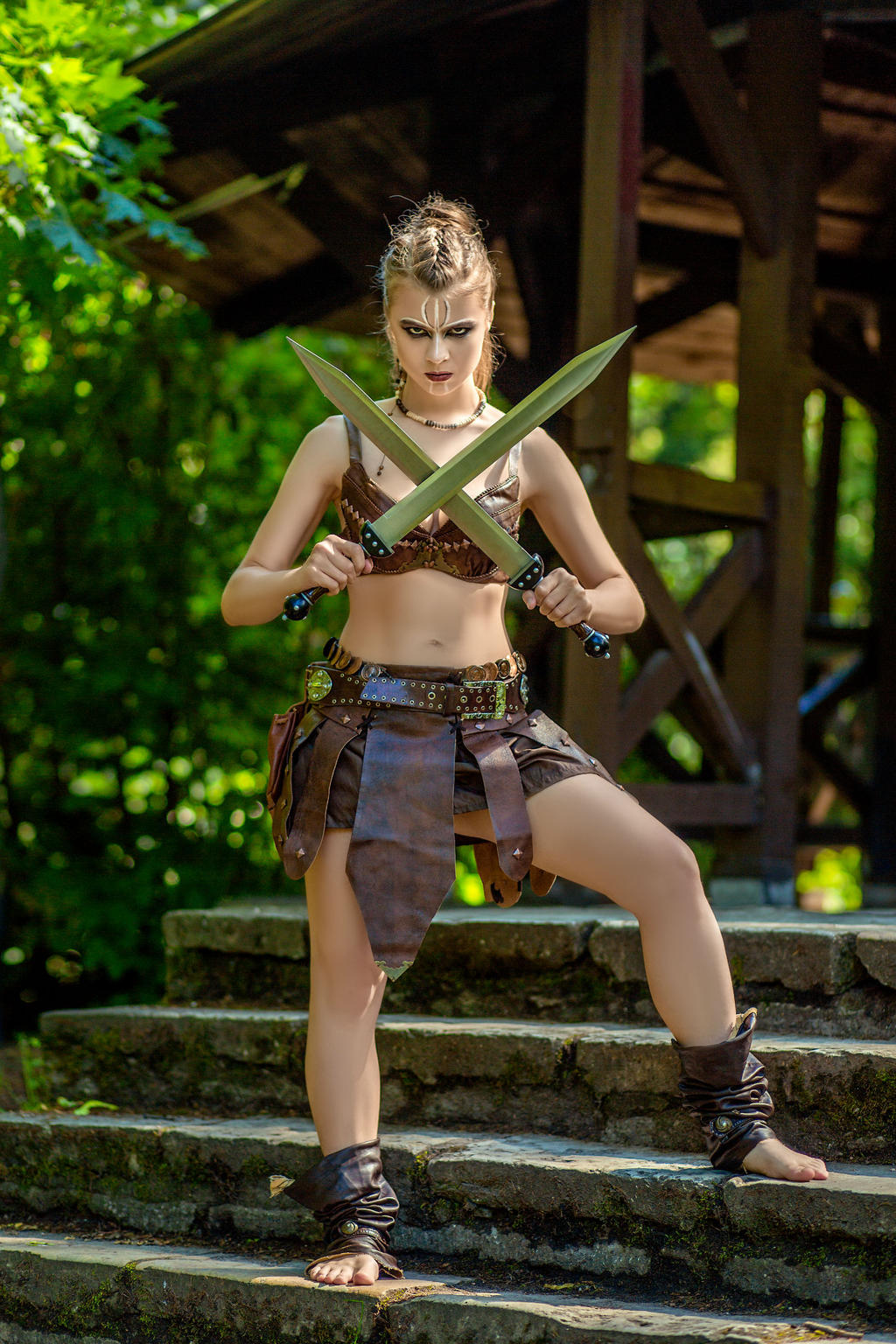 a fierce female warrior, adorned in a leather skirt and armor, stands on a stone staircase in a forest setting. she confidently holds two swords crossed in front of her, her body paint adding to her formidable appearance. the scene evokes a sense of strength, determination, and ancient battle.