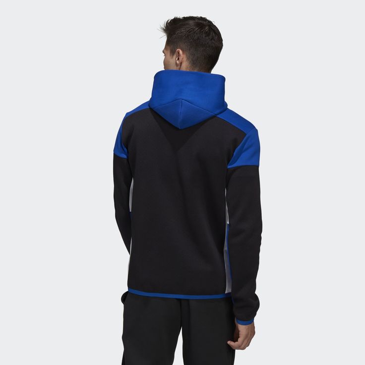 a man is wearing a black adidas hoodie with blue and white accents.  the hoodie is a zipup style and has a hood. the man is wearing black pants.  the hoodie appears to be made of a comfortable, athletic material.  the hoodie is from the adidas brand.  the man is facing away from the camera.  the background of the image is white.