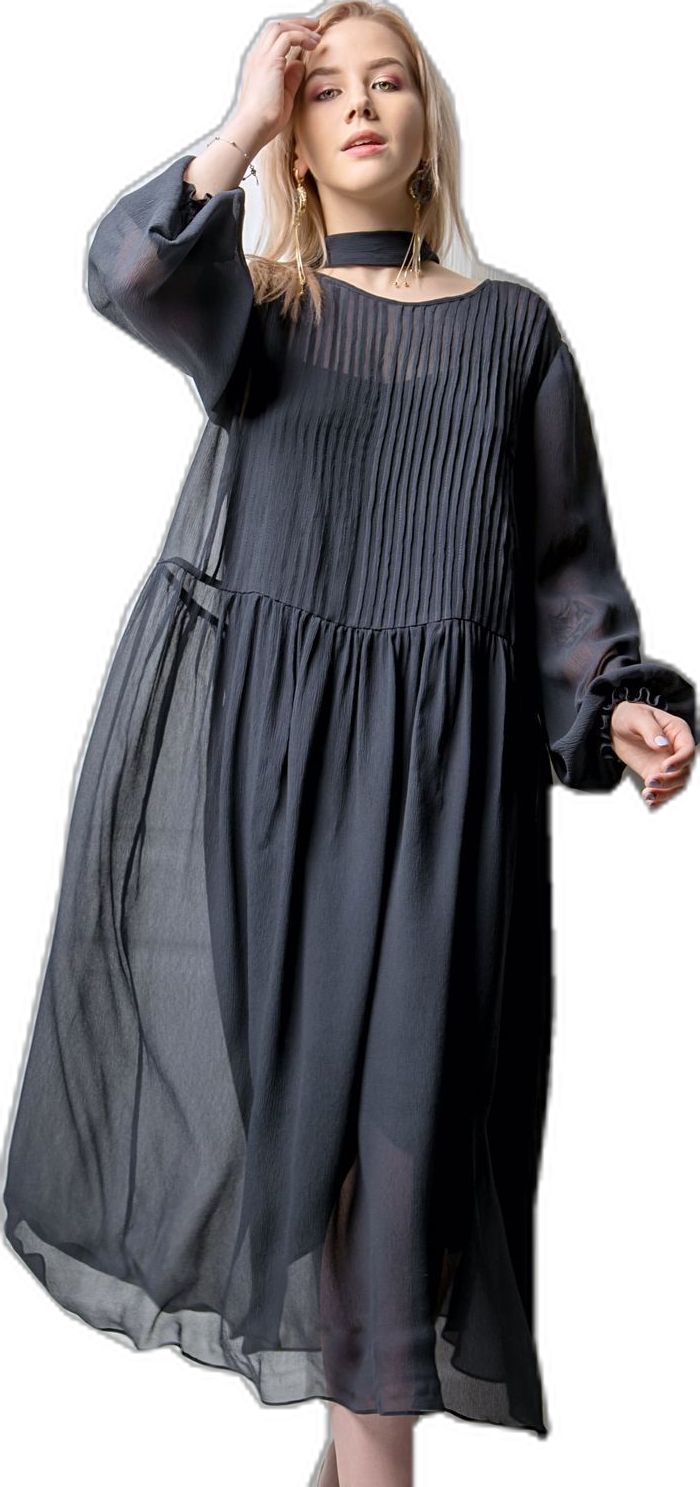 a woman wearing a black chiffon dress with long sleeves. she is posing for a photo in a studio. she has on a black choker necklace. the dress is flowy and has pleats. her hair is down, and she is looking at the camera with a light smile.