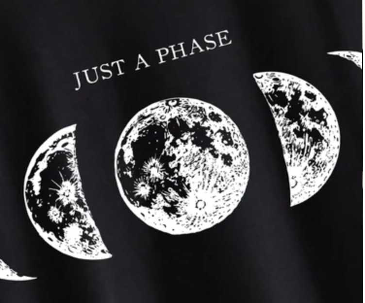 a black tshirt with the words "just a phase" above three illustrations of the moon in different phases: waxing crescent, full moon, and waning gibbous.