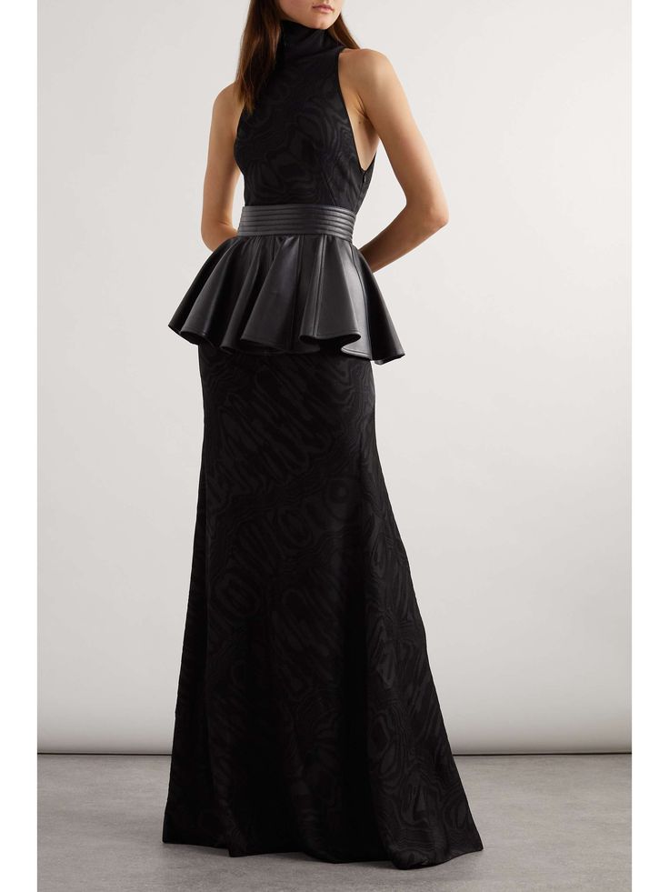 a woman in a black gown with a zebra print pattern and leather belt stands in a pose, staring directly at the camera. she is wearing a mock neck top, black heels and has her hair pulled back. the dress is fitted at the top and flares out at the waist. she looks elegant and stylish.