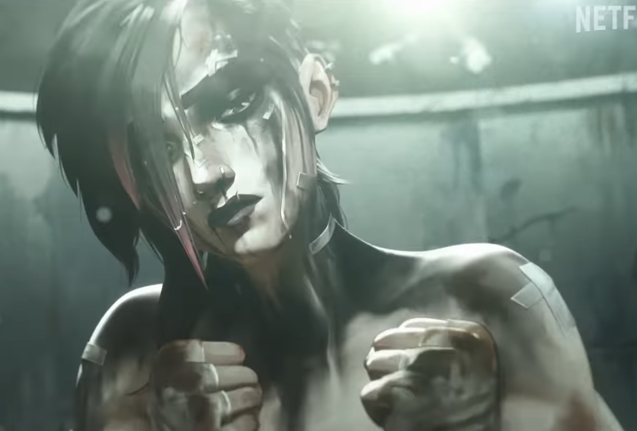 a woman with dark hair and a serious expression is looking at the viewer. she is covered in scars and tattoos, and she appears to be a warrior or fighter. she is positioned in a fighting stance, and her expression conveys a sense of power and determination.
