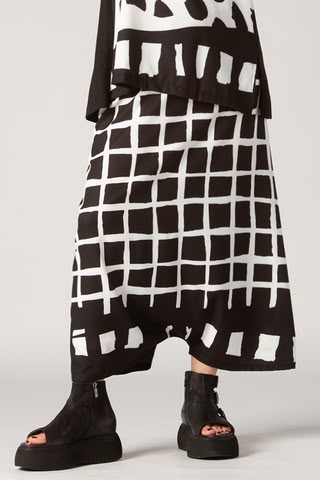 a person is wearing a black and white patterned outfit with opentoe platform boots. the outfit consists of a top and culottes, with a bold black and white pattern. the boots are black and have a platform sole.