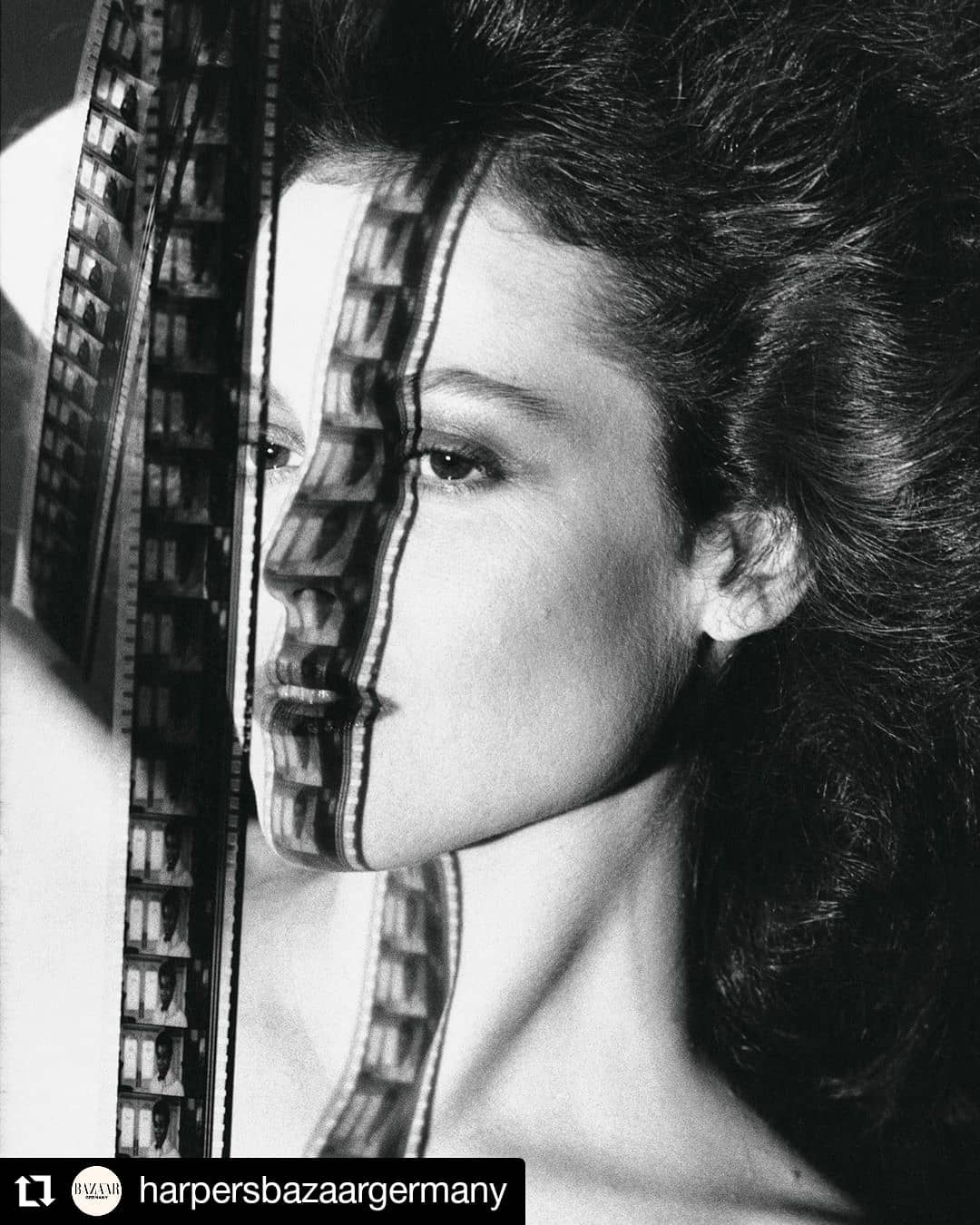 a black and white photo of a woman's face. the photo was taken with a film camera and the film is visible in the image, creating a unique and vintage aesthetic. the woman has long dark hair and is looking off to the side. she is dressed in a simple outfit, but she looks very elegant and stylish. her eyes are piercing and her lips are full and pouty. the image is a classic example of beauty and style.