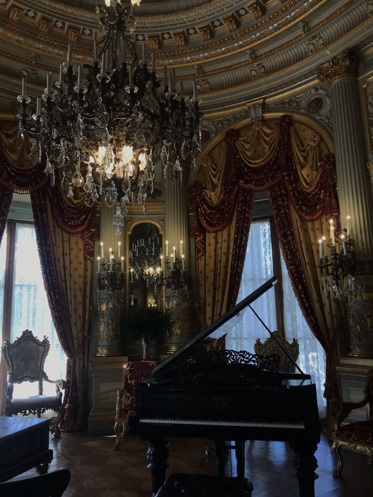 he image shows a grand, dark interior space, possibly in a mansion or palace. a large, ornate crystal chandelier hangs from the domed ceiling. the walls are adorned with rich gold and burgundy curtains, framing large windows that allow soft, diffused light into the room. a black grand piano is centrally positioned, its open lid creating a dramatic visual element. there's an antiquestyle chair to the left, and the overall atmosphere is elegant, luxurious, and slightly mysterious, suggesting a sense of oldworld grandeur and opulence. the lighting is dim, creating a moody yet inviting ambiance.  several candleabras further add to the dramatic lighting of the room.