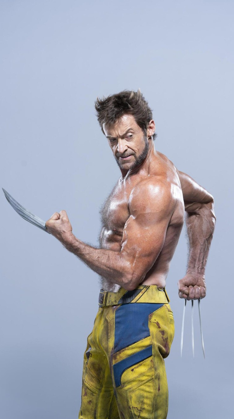 a fullbody shot of hugh jackman as wolverine. he is shirtless and wearing yellow and blue pants. his claws are extended on both hands. he has an angry expression.