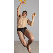 a muscular man is suspended in midair, captured in a dynamic pose against a simple studio backdrop. the image highlights his physique and athleticism.