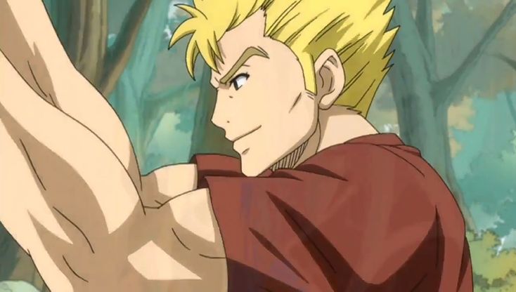 this is an anime still from a show. it's a close up of a muscular male anime character. he has blond hair and is wearing a red shirt. his arm is extended outward as he is smiling. the background is a blurred green forest.
