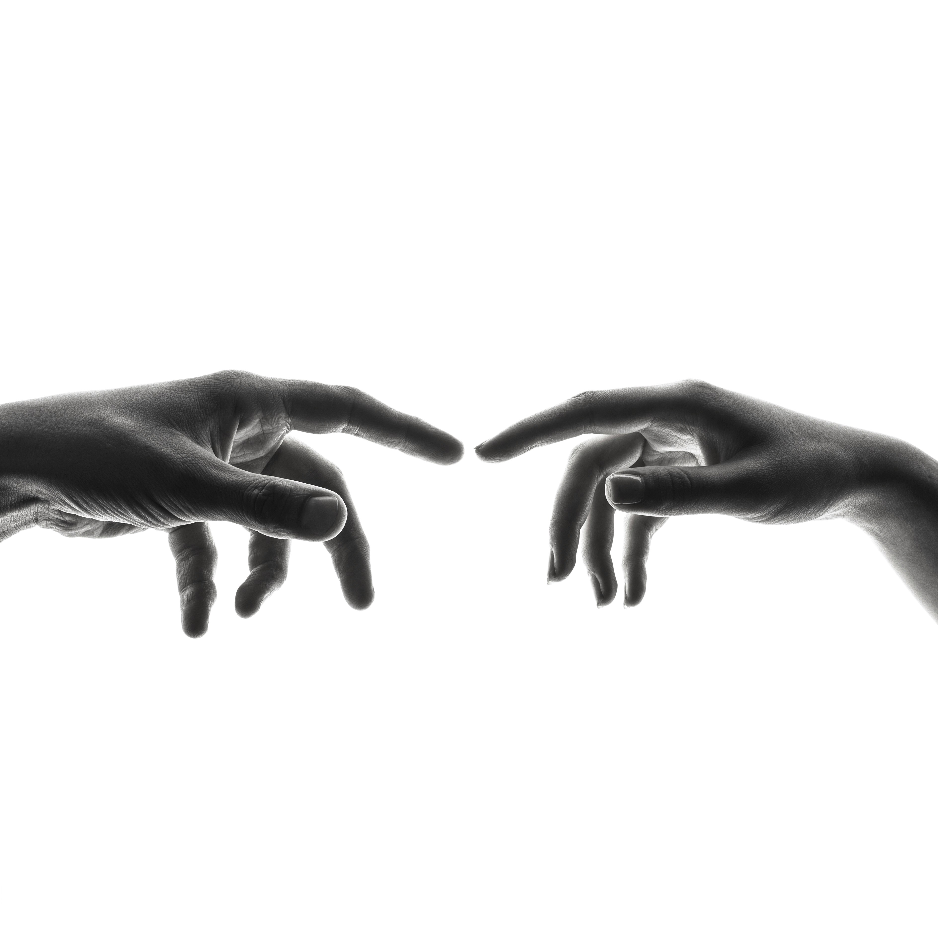 the image showcases a black and white photograph of two hands reaching towards each other, their index fingers about to touch.  it's a clear homage to michelangelo's "the creation of adam" fresco. the highcontrast lighting emphasizes the shape and texture of the hands against a pure white background.