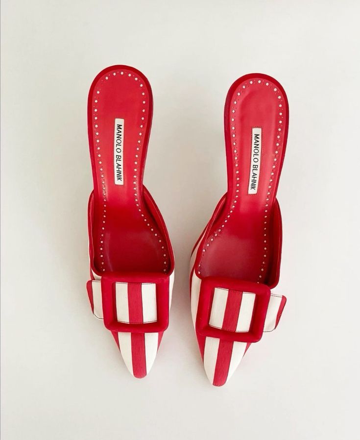 the image shows a pair of manolo blahnik women's mules.  the shoes are a striking red and white striped fabric with a pointed toe and a distinctive buckle detail on the vamp.  the heels are a medium height, and the shoes are presented on a light background, showcasing the detail of the shoes and the designer's label visible on the inside. the shoes appear new or in excellent condition.