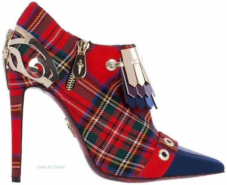 he image shows a single women's highheeled ankle boot. the boot is predominantly red plaid with a navy blue pointed toe cap.  it features gold metal accents, including a decorative element at the top and a zipper detail.  tassels in shades of blue and purple hang near the ankle. the heel is thin and stilettolike. the background is plain white, allowing the shoe to be the focus.  a small watermark indicating "crazy for shoes?" is visible.